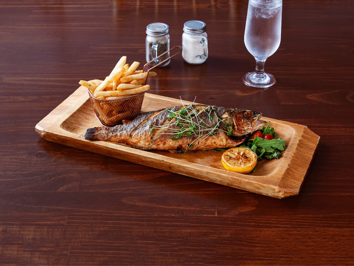Whole baked rainbow trout with fries and grilled lemon